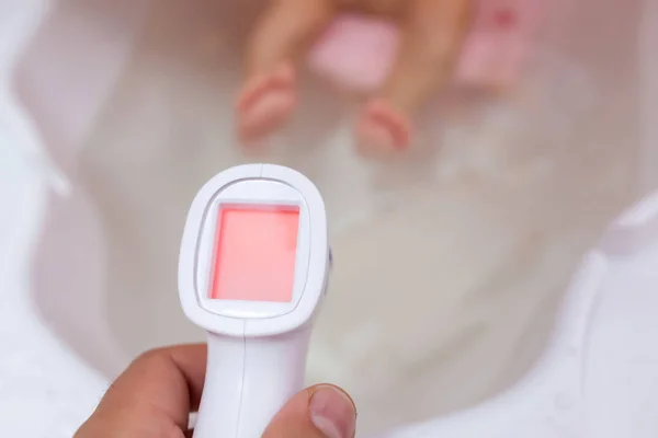 Temperature control with an infrared thermometer in the bathroom when bathing a newborn