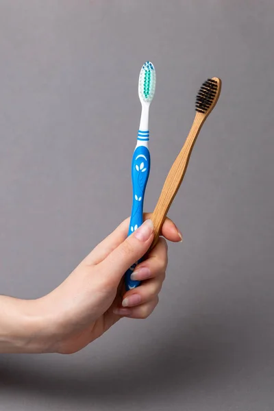 Στοματική Υγιεινή Χέρι Μιας Γυναίκας Κρατά Μπαμπού Και Πλαστικές Οδοντόβουρτσες — Φωτογραφία Αρχείου