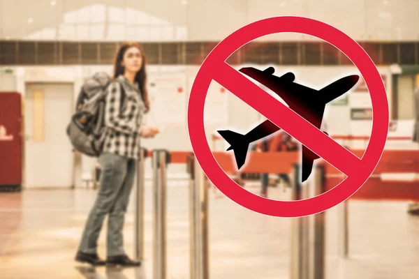 A woman stands at the airport, with a backpack on her shoulders, waiting for the plane to take off. Blurred. Cancelled sign.The concept of a ban on flights, closure of state borders and a virus pandemic.