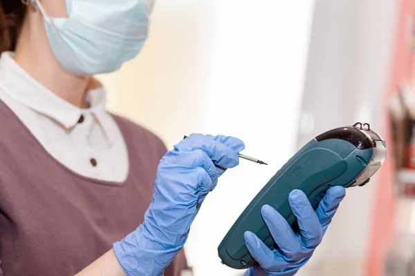 Small businesses during the pandemic. Worker in a medical mask holding a Bank terminal for payment and entering information with a stylus. Concept of protection against coronavirus.