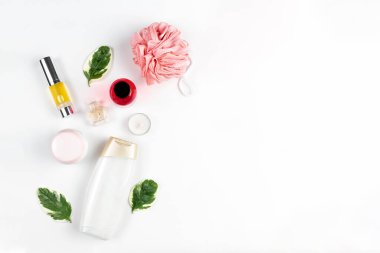 Kozmetik ve kişisel bakım. Yeşil yapraklar, havlular, duş jeli, parfüm, tüpteki yağ ve beyaz arka planda bir mum bileşimi serilmiştir. Düz yat ve boşluğu kopyala.