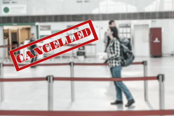 A woman stands with a backpack in airport, waiting for the plane to take off. Blurred. Cancelled sign.The concept of a ban on flights, closure of state borders and a virus pandemic.