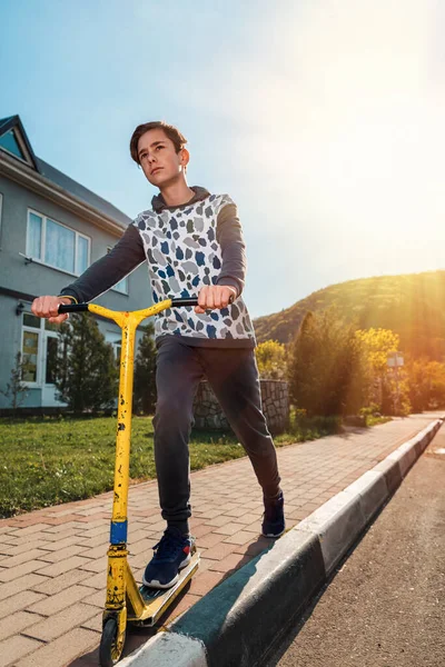 Puberťák Vážným Obličejem Jezdí Skútru Chodníku Pozadí Prázdná Ulice Spodní — Stock fotografie