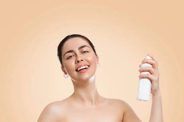 若い白人女性は ぬれた肌で笑顔で 化粧品のボトルを持っています コピースペース ベージュの背景 スキンケア 日焼けの概念 — ストック写真