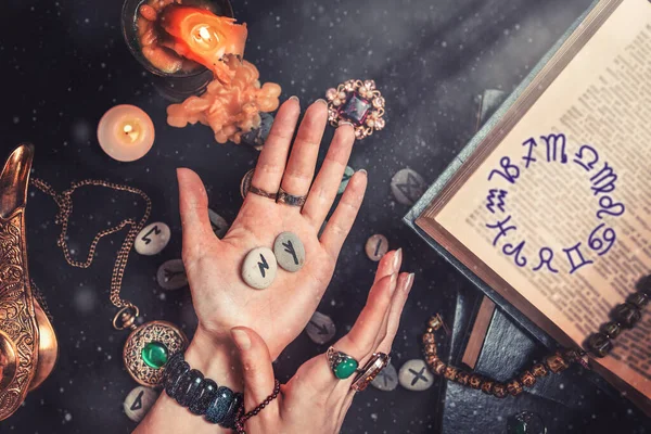 占星術と美学 魔女は彼の手の中にルーンの石を保持しています 黒の背景に占いランで 貴重なお守り 銅ランプとキャンドル — ストック写真