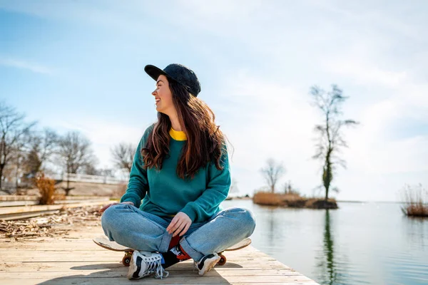 Eine Junge Kaukasierin Sitzt Schneidersitz Auf Einem Skateboard Und Schaut — Stockfoto