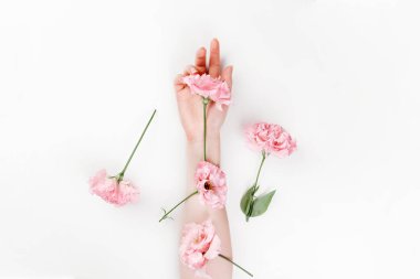Üzerinde pembe Eustoma çiçekleri olan narin bir kadın eli. Beyaz arka plan. Düz yatıyordu. Uzayı kopyala Çiçekçilik ve şefkat kavramı.