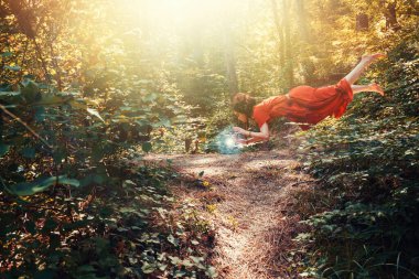 Fantezi. Elf, Druid ya da peri şeklinde genç esmer bir kadın enerji topunun üzerinde geziniyor. Orman arka planda.