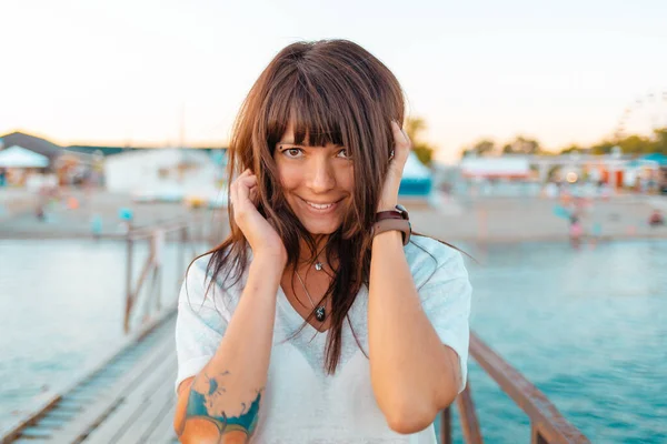 海のそばの木製の桟橋に入れ墨をしたかなり幸せな女性の肖像画 夏休みのコンセプト — ストック写真
