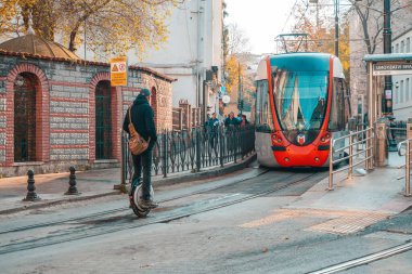 18.12.2019, İstanbul, Türkiye. Tek tekerlekli bisiklete binen bir adam var. Arka planda bir tramvay var. Şehir ulaşımı.