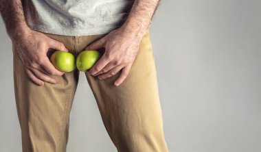 Üreme organı seviyesinde, olgun ve çürük bir elma tutan bir adam. Erkekler için hastalık. Cinsel yolla bulaşan enfeksiyonları koruma kavramı. Boşluğu kopyala.