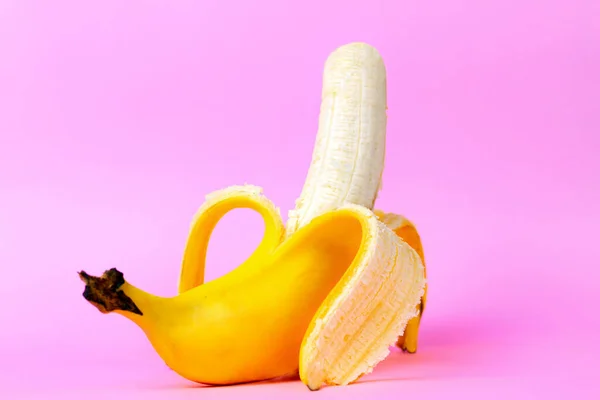 An open banana symbolizing the male sexual organ in an erect state. Pink background. Concept of potency and men\'s health and strength. Copy space.