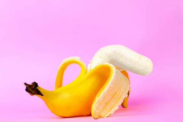 An open banana symbolizing the male sexual organ in an UN-erect state or impotence. Pink background. Concept of potency and men\'s health and power. Copy space