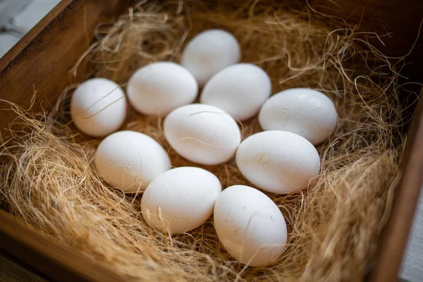 Eco-product. A wooden box of hay containing a ten white eggs. View from the top. Concept of natural and farm food.