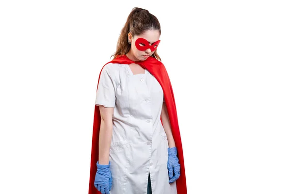 A tired doctor wearing face mask, gloves and a red superhero cape. Isolated on white background. The concept of the Power of a super hero for medicine and stress at work.