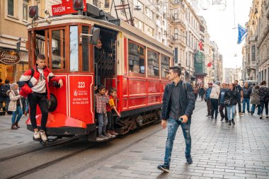 23.10.2019 İstanbul, Türkiye. İstanbul caddesi boyunca klasik kırmızı tramvay turları. Arka planda insanlar otobüs durağına yürüyor. Seyahat kavramı.