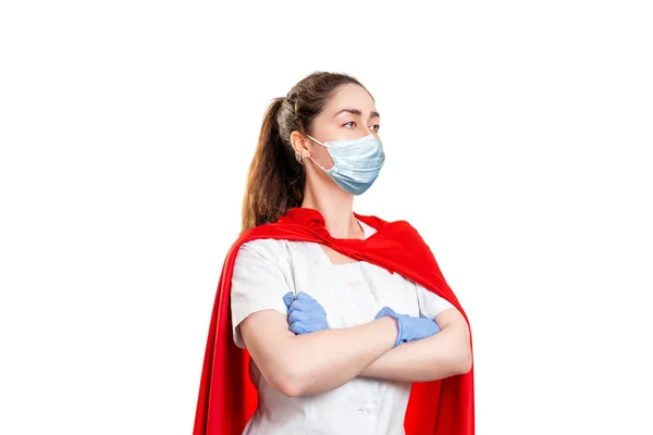 A doctor wearing in a medical face mask, gloves and a superhero Cape, ready to work. Isolated on white background. The concept of the Power of a super hero for medicine.