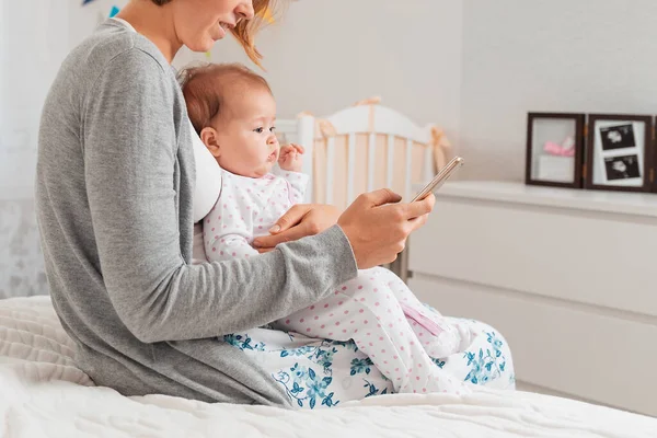 A mother holds a child in her arms and uses a smartphone. Portrait of a child. Concept of motherhood and the dangers of airwes for baby.