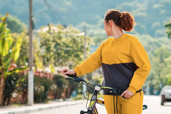 스포츠 운동복을 자전거를 돌아보는 여자의 뒤에는 도로와 있습니다 Eco Friendly — 스톡 사진