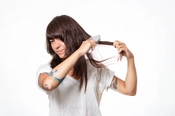 入れ墨をした女性は 髪のロックを組み合わせ 痛みを経験し 彼女の髪を引き出す 白地だ コピースペース 脱毛とケアの概念 — ストック写真