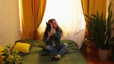 Esmer bukleli kadın model. Rahat iç mekanda saç kurutma, saç bakımı, güzellik ve kişisel rutin. Geniş açı