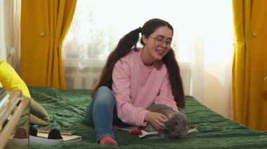 Rahat bir odada rahat bir şekilde oturan genç beyaz kadın tavşanına sarılıyor, evcil hayvan bakımı kavramı ve sakin bir atmosferi olan evcil hayvan sevgisi..