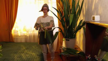 Doğal ışık, çevre hobisi ve günlük hayatta sürdürülebilirliği olan rahat bir dairede bitki yapraklarını buduyor. Geniş açı