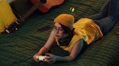 Rahat süveter giyen odaklanmış öğrenci elinde joystick ile evde dijital etkileşimli oyun ve eğlencenin tadını çıkarıyor..