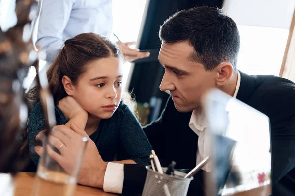 father calming daughter while wife signing documents on divorce