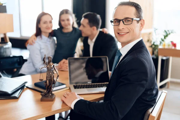 Family lawyer sitting at table with divorcing family at background