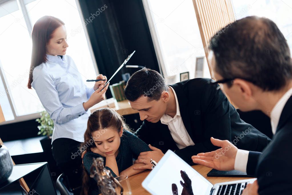 father calming daughter while wife signing documents on divorce