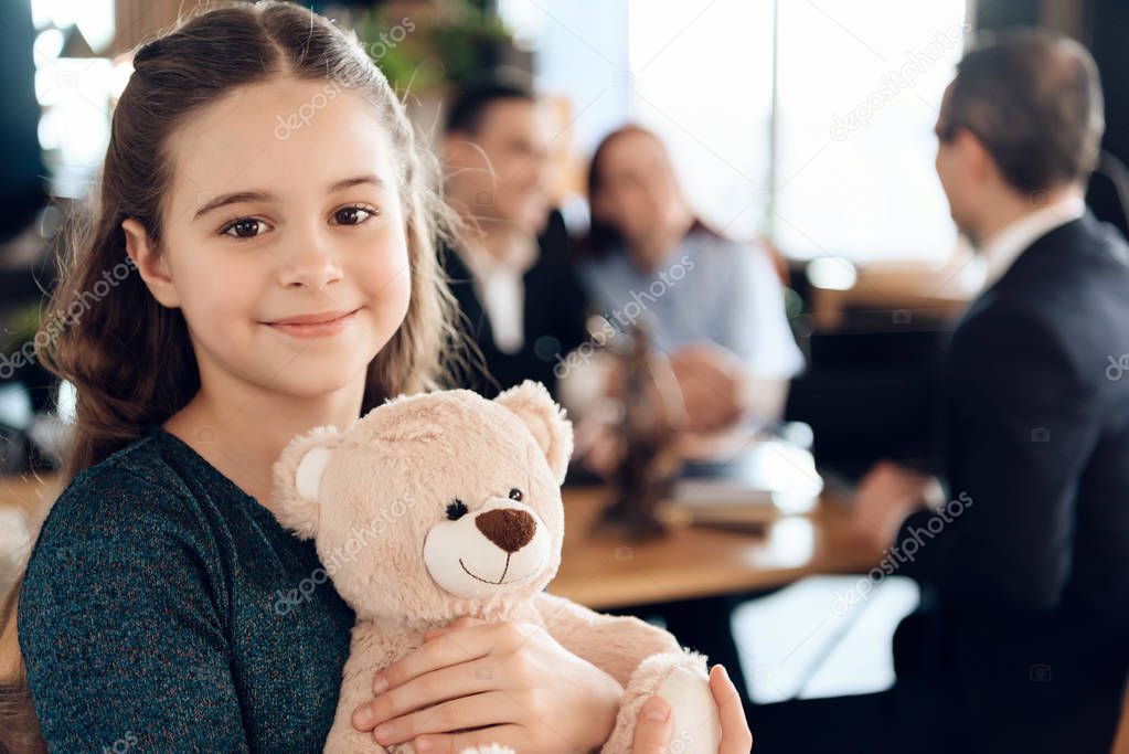 little girl hugging teddy bear at office of family lawyer