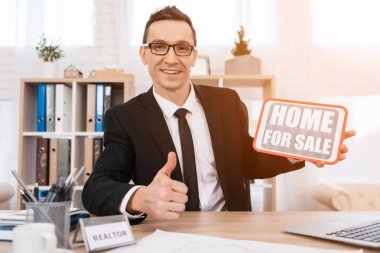 ofiste oturan ve işareti Satılık Ev tutan Emlak 