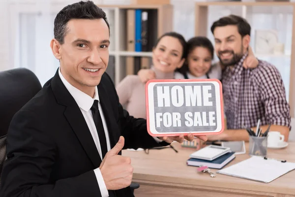 realtor holding sign home for sale in real estate agency