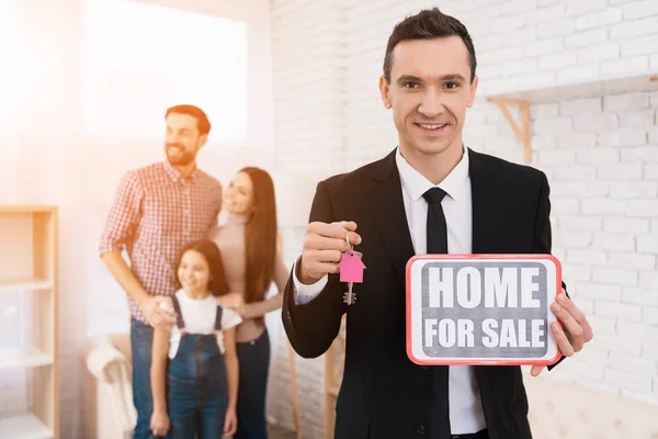 realtor holding sign home for sale and keys in real estate agency