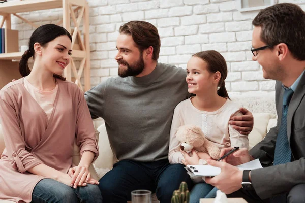 Joyful family sitting on sofa in family psychologist office