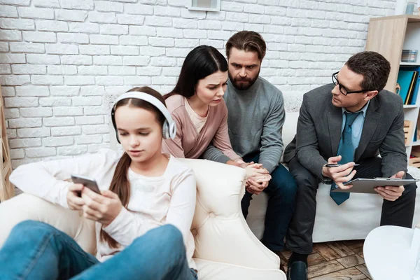 Frustrated parents looking at little daughter while she refusing listen them in psychologist office