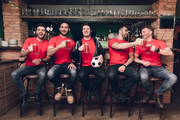 Futbol hayranları oyunu izlerken ve spor bar, kırmızı takım destekleyen, bira içmek