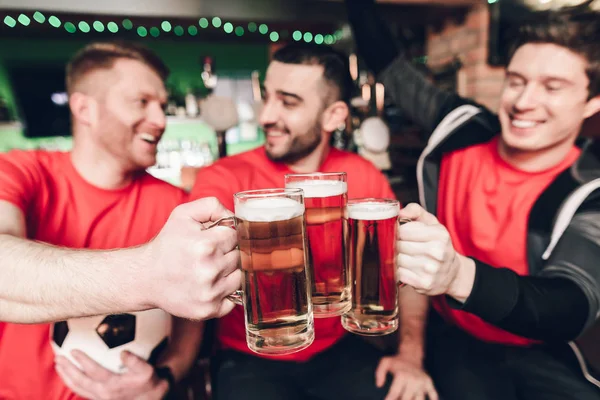Sports fans celebrating and cheering drinking beer at sports bar