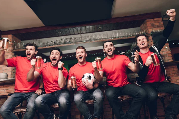 Futbol hayranları oyunu izlerken ve akşam spor barında bira içme Grup