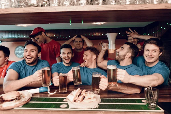 Kutluyor ve arka plan üzerinde üzgün rakipler ile spor barında tezahürat mavi takım taraftarları