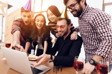 Genç ofis çalışanları birlikte dizüstü bilgisayara bakıyor. Ellerinde şampanya bardakları var. Keyifleri yerinde..