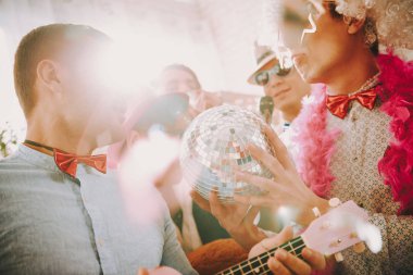 Bir adam, eşcinsel arkadaşına disko topu gösterir..