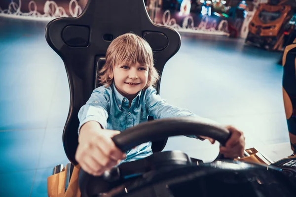 Garçon assis dans une chaise de jeu vidéo et voiture de conduite. — Photo