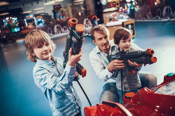 Papá enseña a sus hijos a jugar juegos de disparos. — Foto de Stock