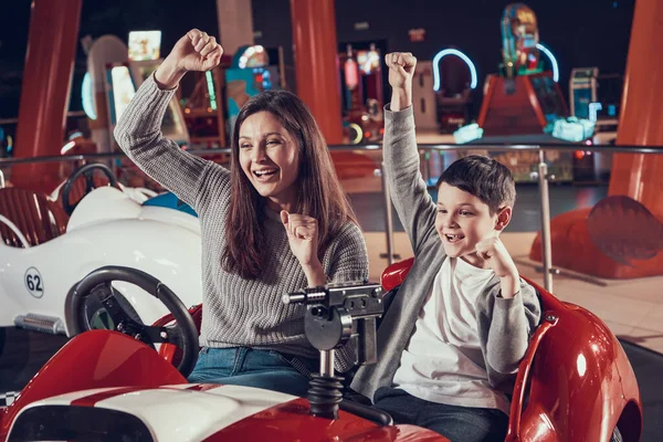 Mamá e hijo se regocijan de que ganaron el juego en el coche de juguete. — Foto de Stock