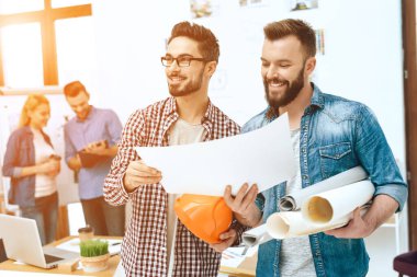 Tasarımcılar gülümsüyor ve bir kağıt parçasına bakıyor..