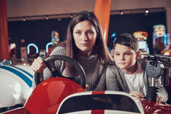 Hijo se sienta al lado de mamá mientras ella conduce un coche de juguete. —  Fotos de Stock