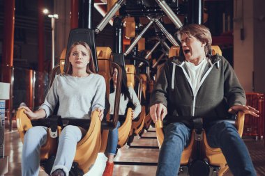Man and girl are afraid to ride a roller coaster. clipart