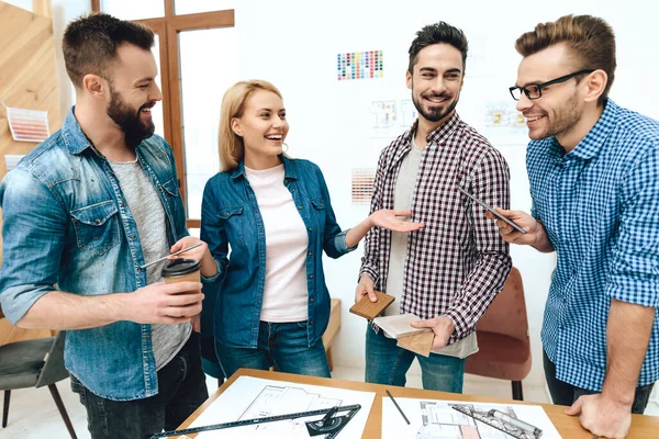 Los diseñadores miran a un hombre con un teléfono y sonríen. — Foto de Stock